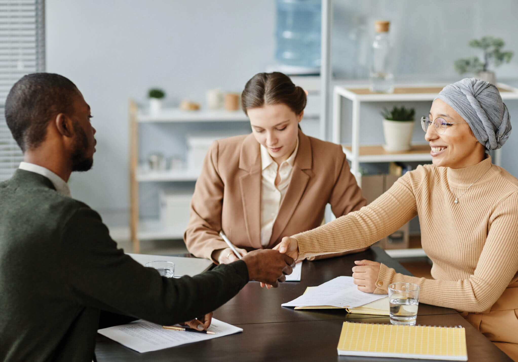 In an office, a woman firmly shakes hands with an interviewee, embodying professionalism. Harness such moments with our short course on Communication & Interview Skills.